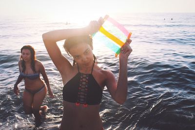 Happy friends standing on beach against sky