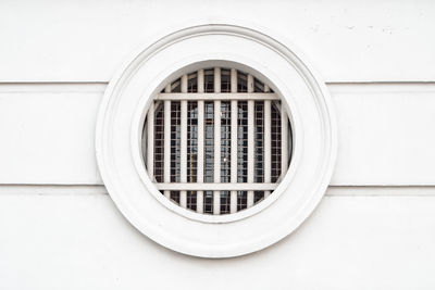 Full frame shot of circle window with trellis on white wall