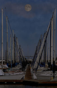 Sailboats moored at harbor against sky
