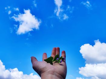 Low angle view of hand against blue sky