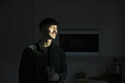 Smiling man with sunlight on face standing in kitchen