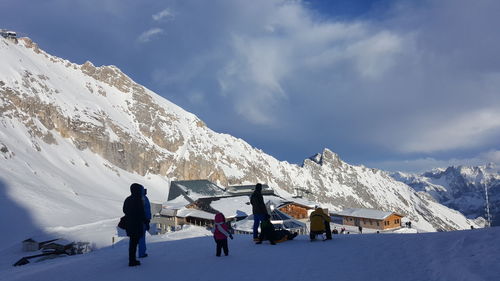 People skiing on snowcapped mountain against sky