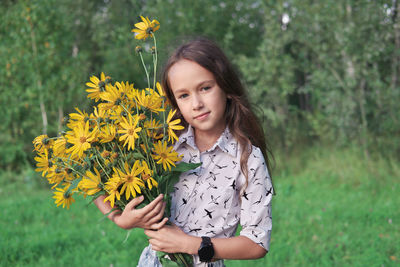 Little girl holding a bouquet of topinambur flowers. bright yellow flowers. summer country concept. 