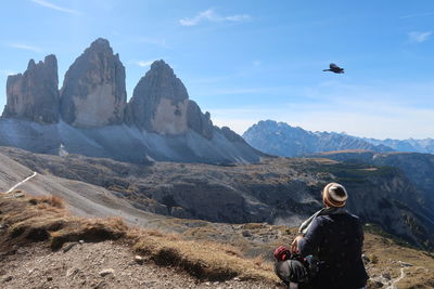 Rear view of man sitting on land against sky