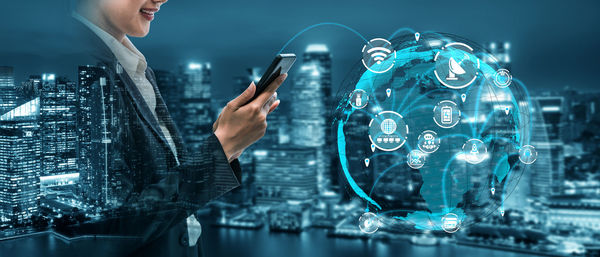 Midsection of woman using mobile phone at illuminated cityscape