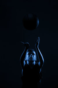 Close-up of boy holding volleyball against black background