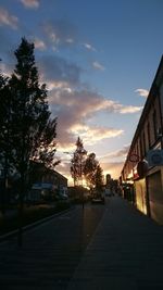 Street amidst buildings against sky during sunset