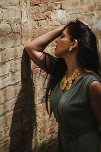 Side view of young woman standing against wall