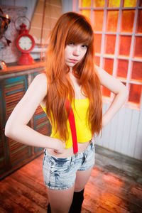 Portrait of smiling young woman standing against wall