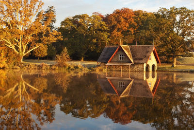 House by lake and trees against sky