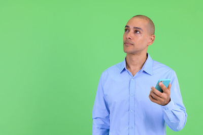 Man holding phone while standing against green background