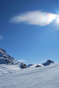 Scenic view of snow covered mountains against blue sky