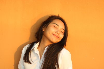 Portrait of a beautiful young woman against orange wall