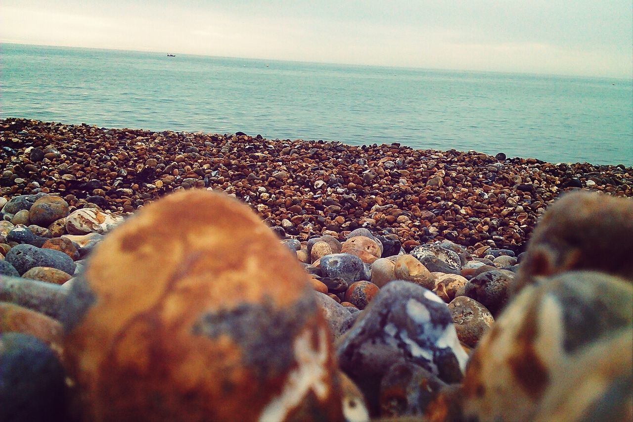 sea, beach, horizon over water, water, shore, pebble, sky, scenics, rock - object, nature, tranquility, sand, lifestyles, beauty in nature, stone - object, leisure activity, tranquil scene, vacations