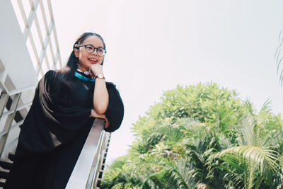 Young woman looking away while standing against plants