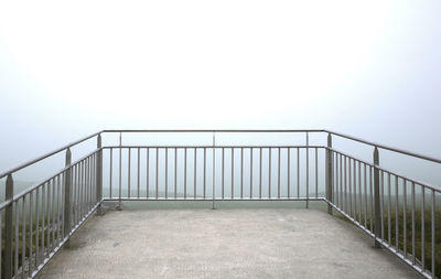 Railing by sea against clear sky