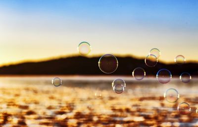 Close-up of bubbles over river against sky