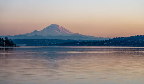 Scenic view of lake by mountains against sky during sunset