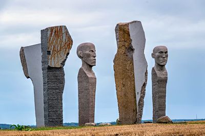 Statues on field against sky