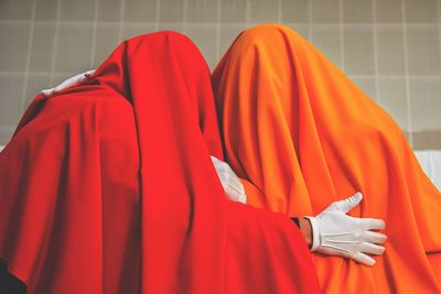 Cropped image of people standing against orange wall