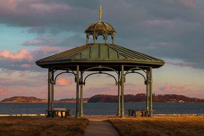 Gazebo on beach against sky during sunset