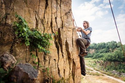 Side view of smiling young man on tree trunk