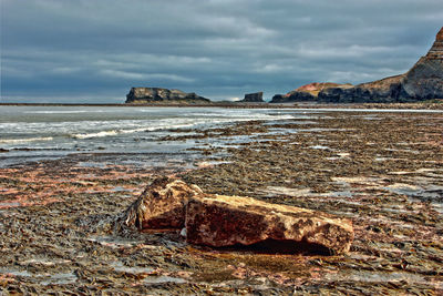 Scenic view of rocks on beach against sky