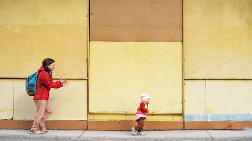 Full length of a boy standing against wall