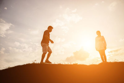 Full length of friends standing on field against sky during sunset