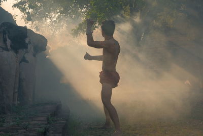 Side view of shirtless man exercising on land