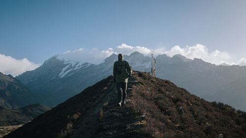 Rear view of man standing on mountain against sky