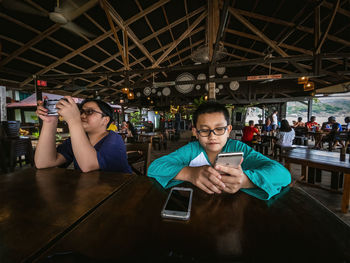 Children sitting at the table and using mobile phone. looking serious.