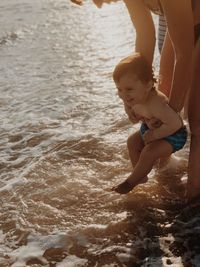 Midsection of mother carrying son in sea