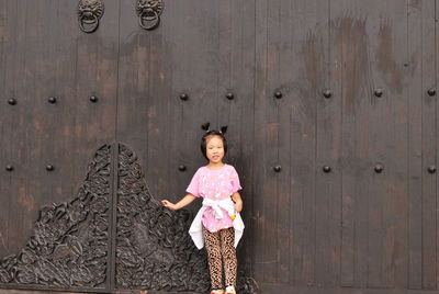 Portrait of smiling girl standing against closed door