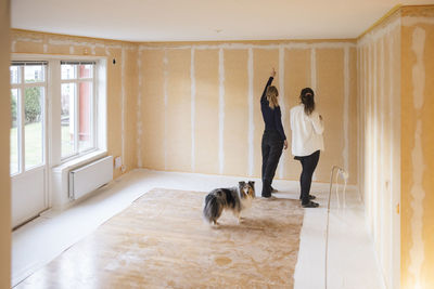 Female painter priming room for painting