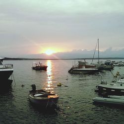 Boats moored on sea against sky during sunset