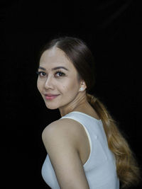 Portrait of young woman against black background