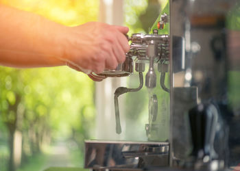 Close-up of person holding portrafilter at espresso maker 