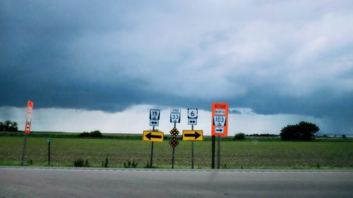 Road signs on field against sky