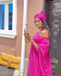 Portrait of woman standing against pink window