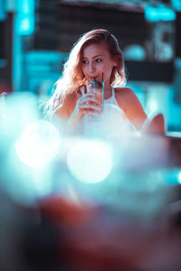 Young woman sitting with drink during sunset