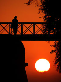 Silhouette man standing against orange sky