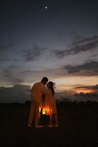 Rear view of woman standing against sky during sunset