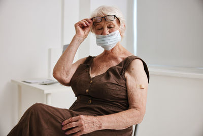 Senior woman with bandage on arm sitting at hospital