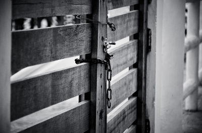 Chain hanging on wooden gate during sunny day