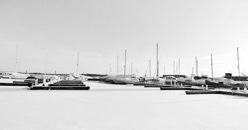 Boats moored at harbor against clear sky