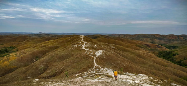 Rear view of man walking on mountain against sky
