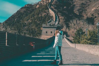 Rear view of woman standing on steps leading towards mountain