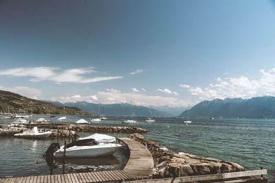 Sailboats moored on sea against sky