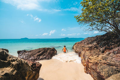 Rear view of woman looking at beach against sky